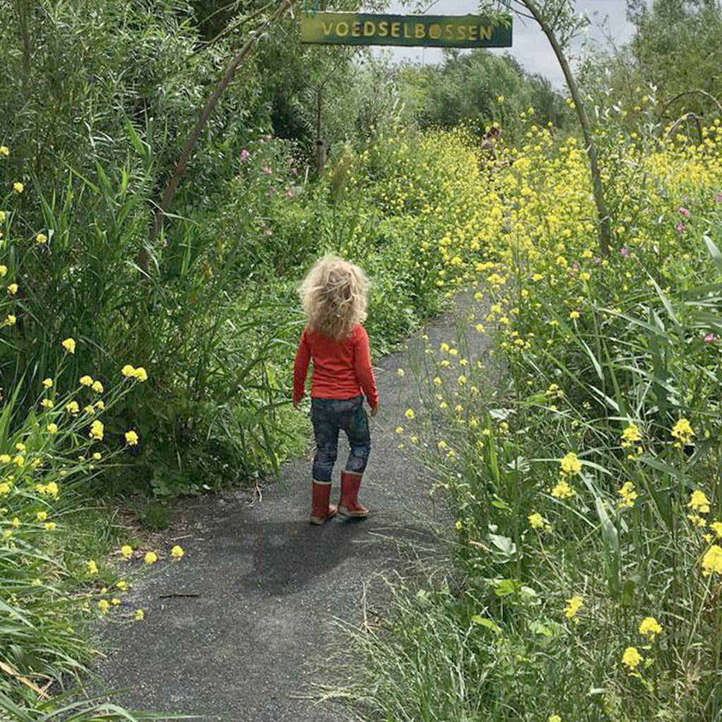 meisje op een pad van greenSand olivijn in het voedselbos van Anna's tuin